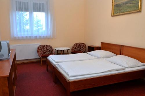 莫尔Belvárosi Vendégház的一间卧室配有一张带两把椅子的床和一张书桌