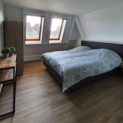 代尔登B&B Kamille的一间卧室配有一张床、一张桌子和两个窗户