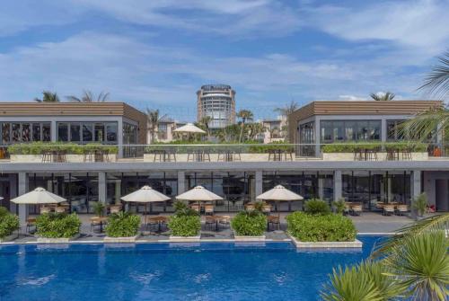 金兰Wyndham Garden Cam Ranh Resort的一个带桌子和遮阳伞的游泳池的度假酒店