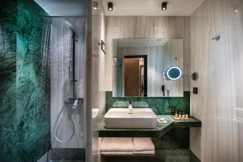 海若克利欧Dimargio Luxury Hotel & Spa的一间带水槽、淋浴和镜子的浴室