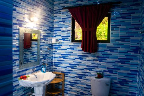 马埃岛贝拉扎尔区Les Elles Guesthouse Self Catering的浴室设有蓝色瓷砖墙壁、水槽和窗户。