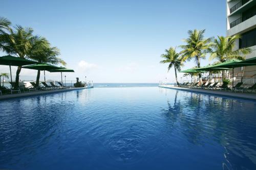 塔穆宁Guam Reef Hotel的一座棕榈树游泳池和一座建筑
