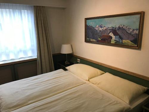 苏黎世中央车站阿莱特酒店的卧室配有一张床,墙上挂有绘画作品