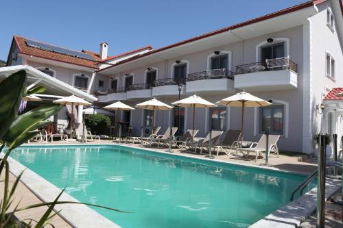 利贾Caretta - Caretta Hotel的一座带椅子和遮阳伞的大楼前的游泳池