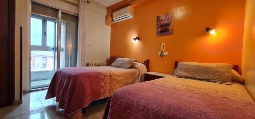 巴利亚多利德拉蒙与卡哈尔旅馆的橙色墙壁和窗户的客房内的两张床