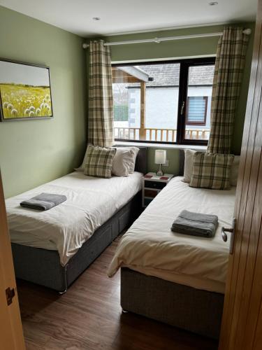 因弗内斯Lesanne Cottage的一间卧室设有两张床和窗户。