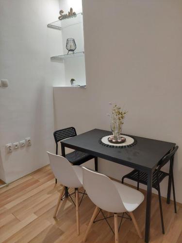 诺维萨德Creative studio 4的一张带白色椅子的黑桌,上面有花瓶
