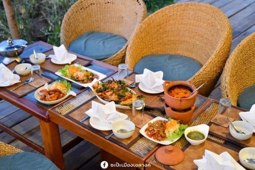南邦KEPT Cabana เคปท์ คาบานา的一张木桌,上面放着食物盘