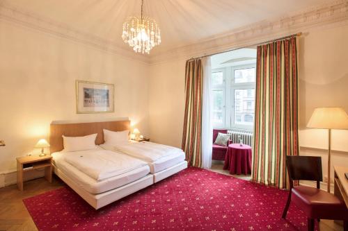 卡尔斯鲁厄马克格拉弗勒酒店的卧室配有一张白色大床和红色地毯。
