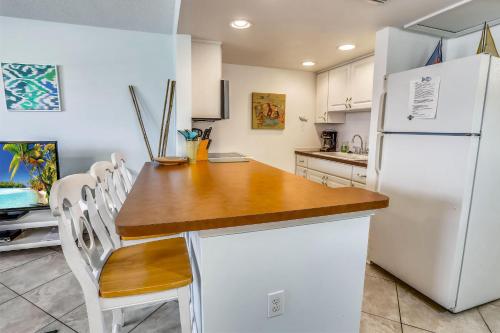 圣徒皮特海滩Sunset Chateau 207的厨房配有白色冰箱、桌子和椅子