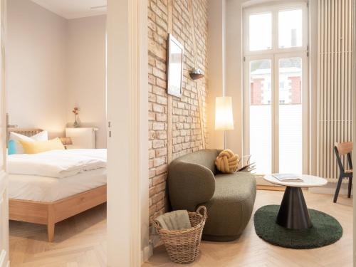 黑灵斯多夫OSTKÜSTE - Villa Groth Design Apartments的卧室配有一张床铺和一把椅子,毗邻砖墙