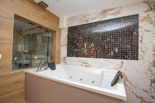 巴尼亚卢卡格兰德酒店的浴室设有白色浴缸和黑色瓷砖墙。