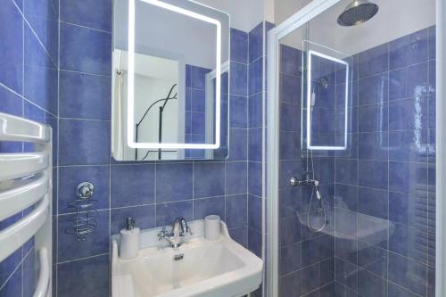 凡尔赛曼德马塞尔公寓的蓝色瓷砖浴室设有水槽和镜子
