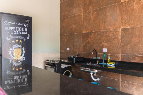 大普拉亚Pousada Vila Real PG的厨房配有水槽和带标志的台面