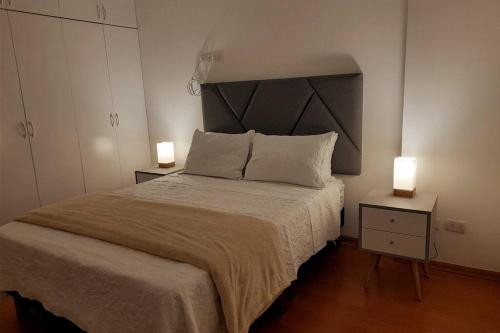 利马Apartment 4 Rent - Av San Borja Norte Cdra 8的一间卧室配有一张大床,桌子上放着两盏灯