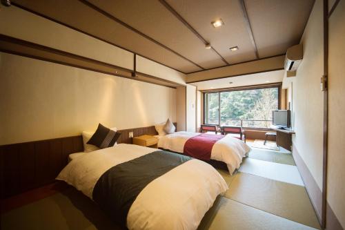 京都Momijiya Honkan Takaosansou的带窗户的客房内的两张床