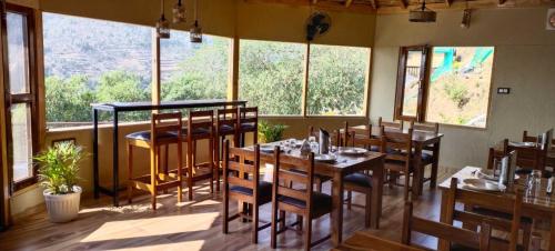 奈尼塔尔Atulyam, Pangot的餐厅设有木桌、椅子和窗户。