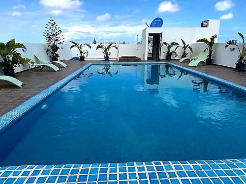 卡萨布兰卡Studio lumineux avec piscine/Gare casa oasis的一座带椅子的大型蓝色游泳池和一座建筑