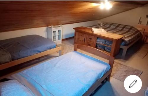 PressinsChambre dans maison a la campagne的客房设有两张床、一张桌子和橱柜。