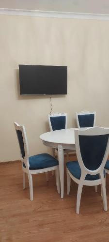 叶海格纳佐尔D&G guest house的一张白色的桌子和椅子,墙上配有电视