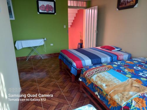 万查科Casa Familiar Eventos y Recepciones Huanchaco Huanchaquito的两张床位于带绿色和色彩缤纷墙壁的客房。