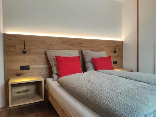 圣坎迪朵Appartements Stoll的一间卧室配有一张带两个红色枕头的床