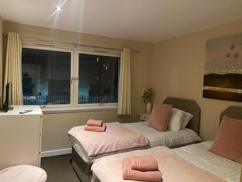格拉斯哥City Centre 2 bedroom apartment, secure parking.的一间卧室配有两张床,上面有粉红色的毛巾