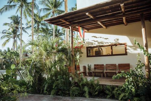 卢纳将军城Vedya Boutique Hostel的一个带木门廊的房屋,配有长椅和棕榈树