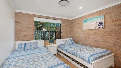 卡尔布拉海滩Beachfront Pool House的一间卧室设有两张床和砖墙