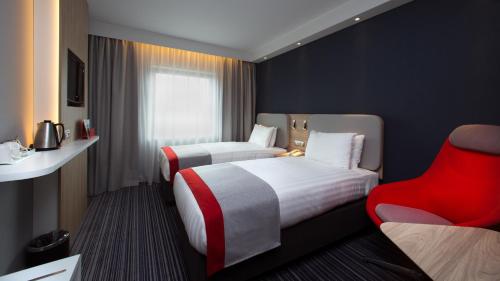 日内瓦日内瓦机场快捷假日酒店的酒店客房,设有两张床和一张红色椅子