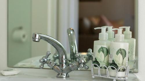 赫曼努斯Eastcliff Cottage的水槽,配有两瓶肥皂和镜子