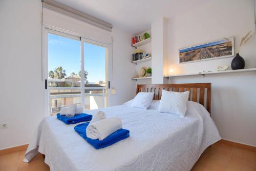 德尼亚Jardines de Denia的卧室配有白色床和蓝色毛巾