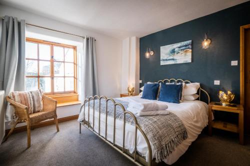 鲍内斯温德米尔Stunning cottage Grade 2 listed with parking and Hot Tub的一间卧室配有一张蓝色墙壁的床和一扇窗户