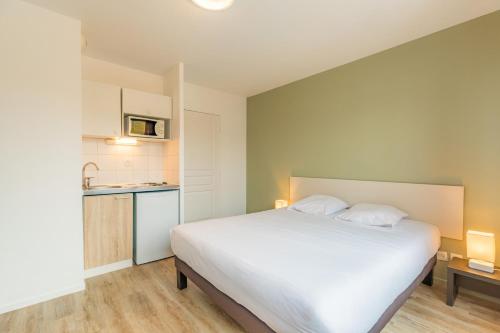 布雷斯地区布尔格Appart'City Classic Bourg-en-Bresse的一间带白色大床的卧室和一间厨房