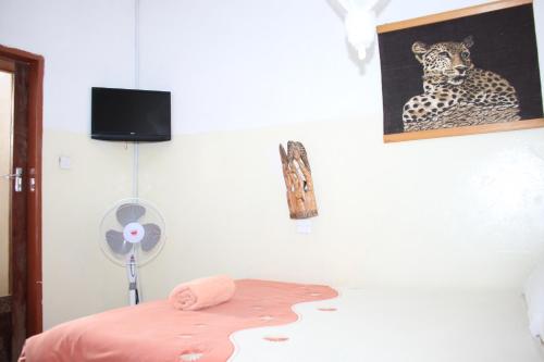 卢萨卡REED MAT LODGE的一间卧室配有一张床和一个风扇,并拥有一张豹子的照片