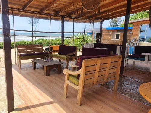 阿姆波尔Love Temple Beach Resort的铺有木地板的凉亭配有长椅和桌子