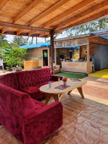 阿姆波尔Love Temple Beach Resort的客厅配有红色的沙发和桌子