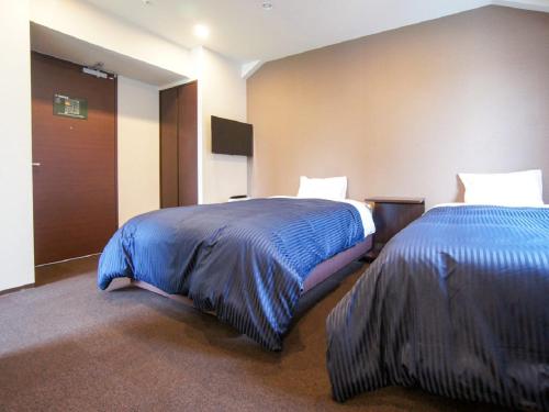 横滨HOTEL LiVEMAX Yokohama Motomachi Ekimae的酒店客房,配有两张带蓝色床单的床