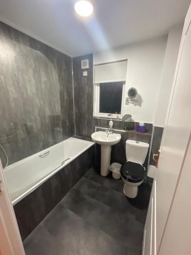 克莱德班克Duntocher village flat的浴室配有盥洗盆、卫生间和浴缸。