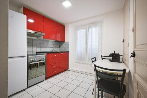戛纳Apparthotel des Congrès et Festivals的厨房配有红色橱柜和桌椅