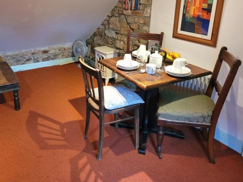 Inch Cross RoadsBallyrider House Beautiful Triple Suite的餐桌、椅子、茶几、杯子和贫穷