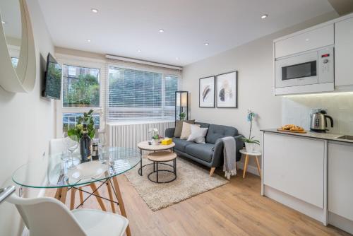 伦敦Westfield Apartment 2 Bedroom near Notting Hill的厨房以及带沙发和桌子的客厅。