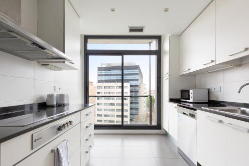 巴塞罗那ChicStays Apartment Vila Olímpica的一间厨房,配有白色的橱柜和大窗户