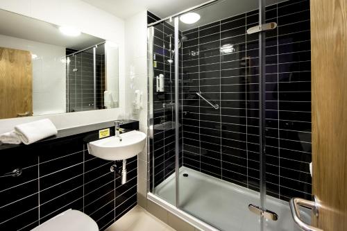 霍尔曼彻斯特机场智选假日酒店的黑色瓷砖浴室设有水槽和淋浴