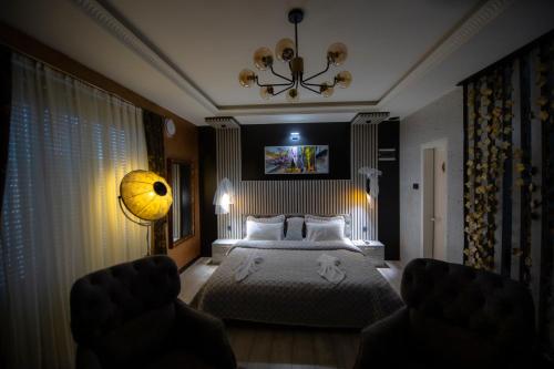 普里什蒂纳Hotel and Apartments Central City Prishtina的一间卧室配有一张床和一个吊灯