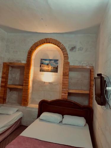 尚勒乌尔法Alkan konuk evi的一间卧室设有两张床和一个拱形窗户。