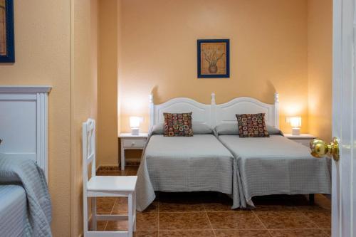 赫雷斯-德拉弗龙特拉Sanvi Xerez Centro的卧室配有白色的床、两张桌子和椅子