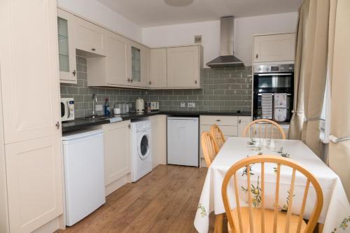 贝克斯希尔Bexhill Luxury Sea Stay Flat 2的厨房配有白色橱柜和桌椅