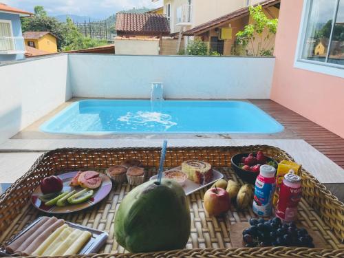 帕拉蒂Casa Premium Paraty com Piscina - Passeio de Escuna de Cortesia incluso的游泳池旁的餐桌上满是食物