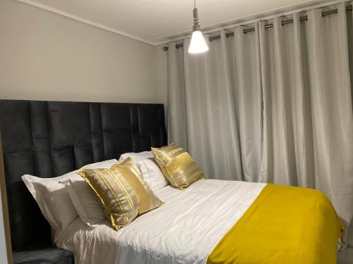 SandownOuter Space - 1 bedroom Luxurious Apartment in Sandton的卧室配有带金色枕头的大床